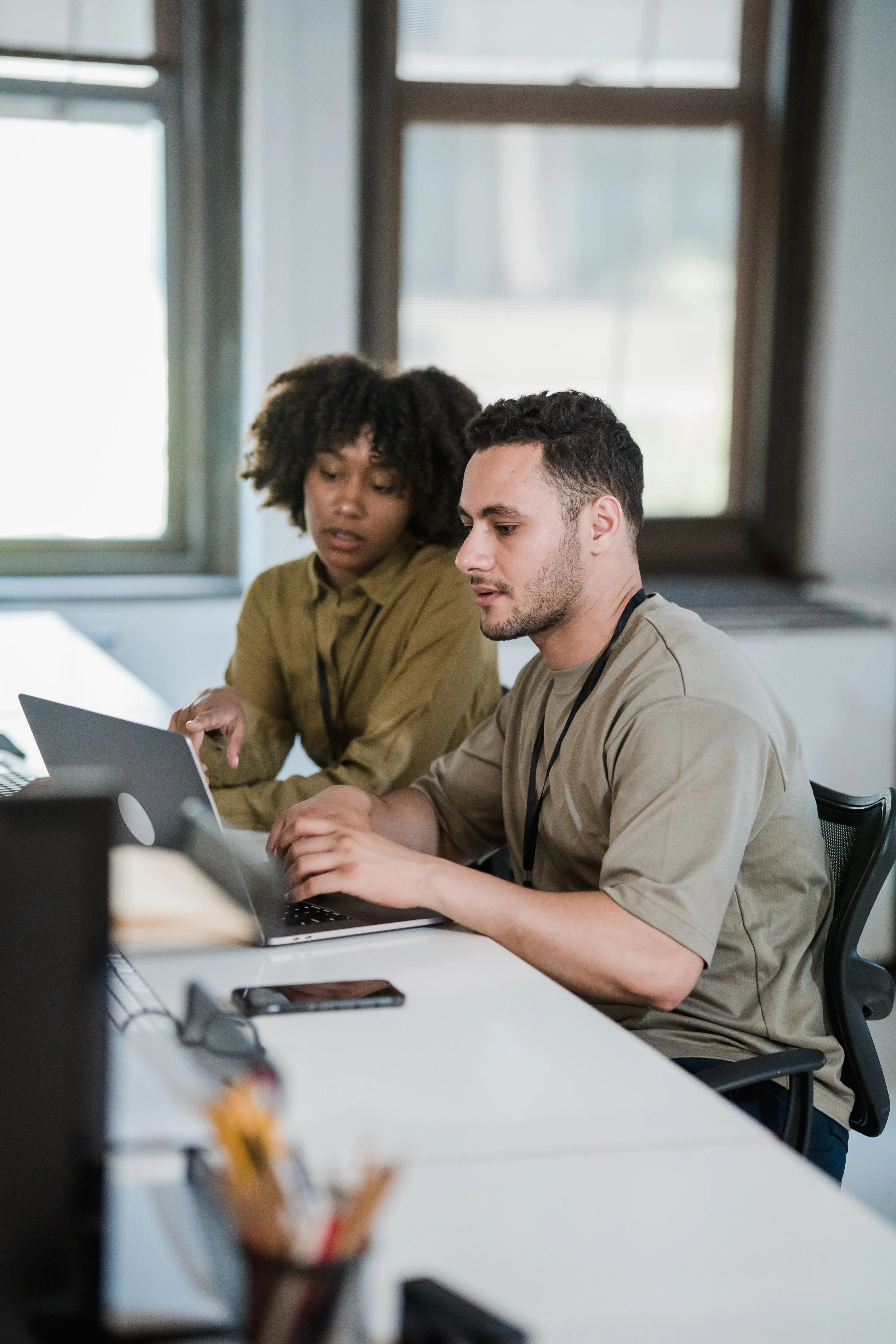 Two young colleagues working through a problem together at a laptop