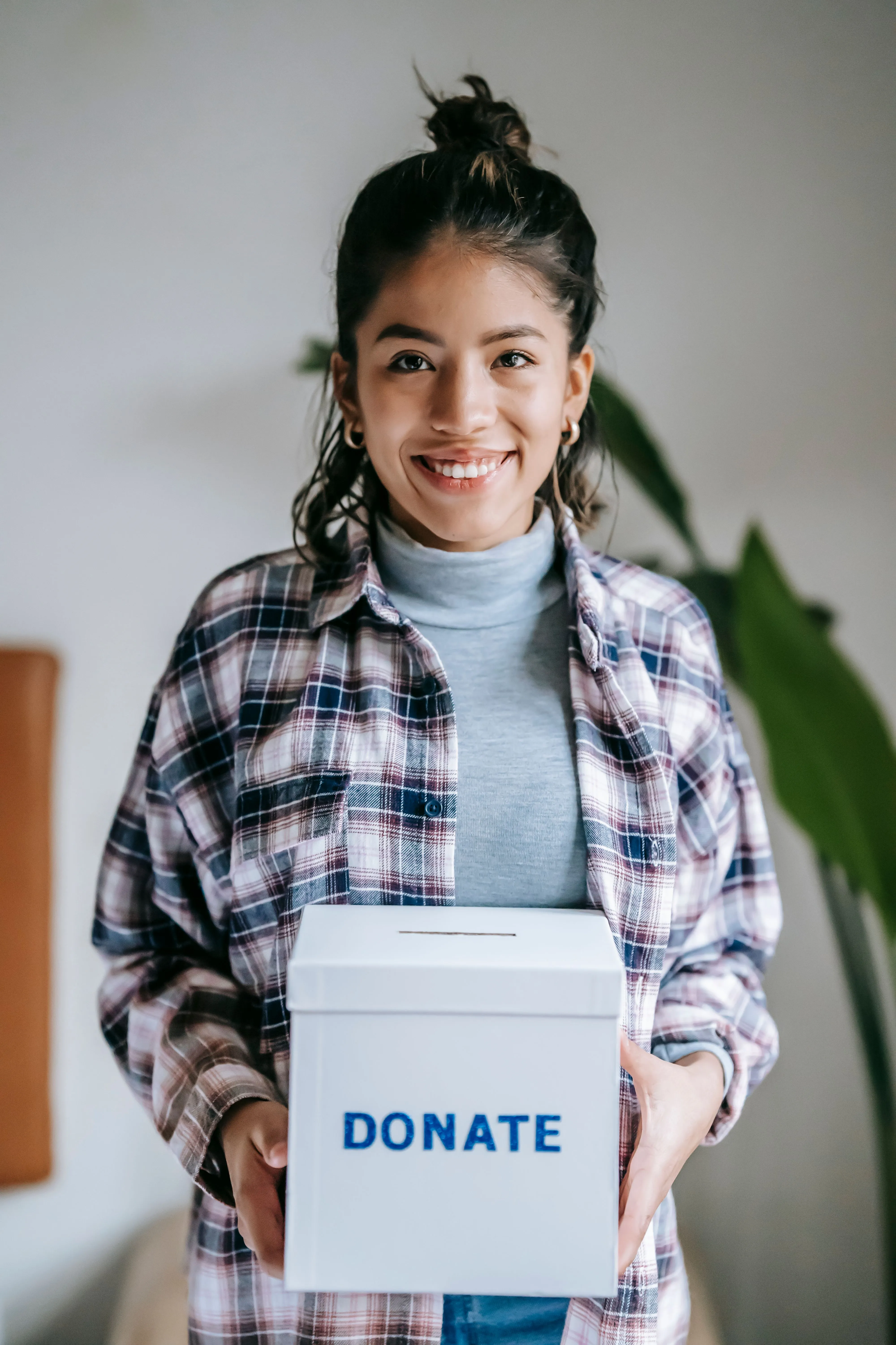 A smiling nonprofit volunteer holding a donation box