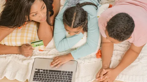 A family lying on a bed together, looking at a laptop