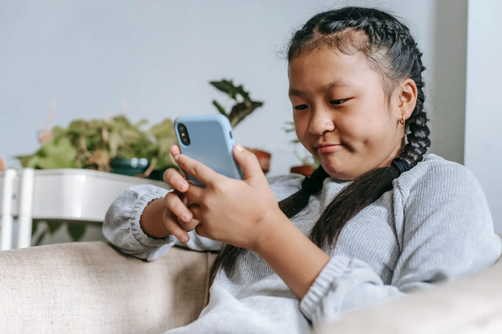 A girl on a couch concentrating on the phone in her hands