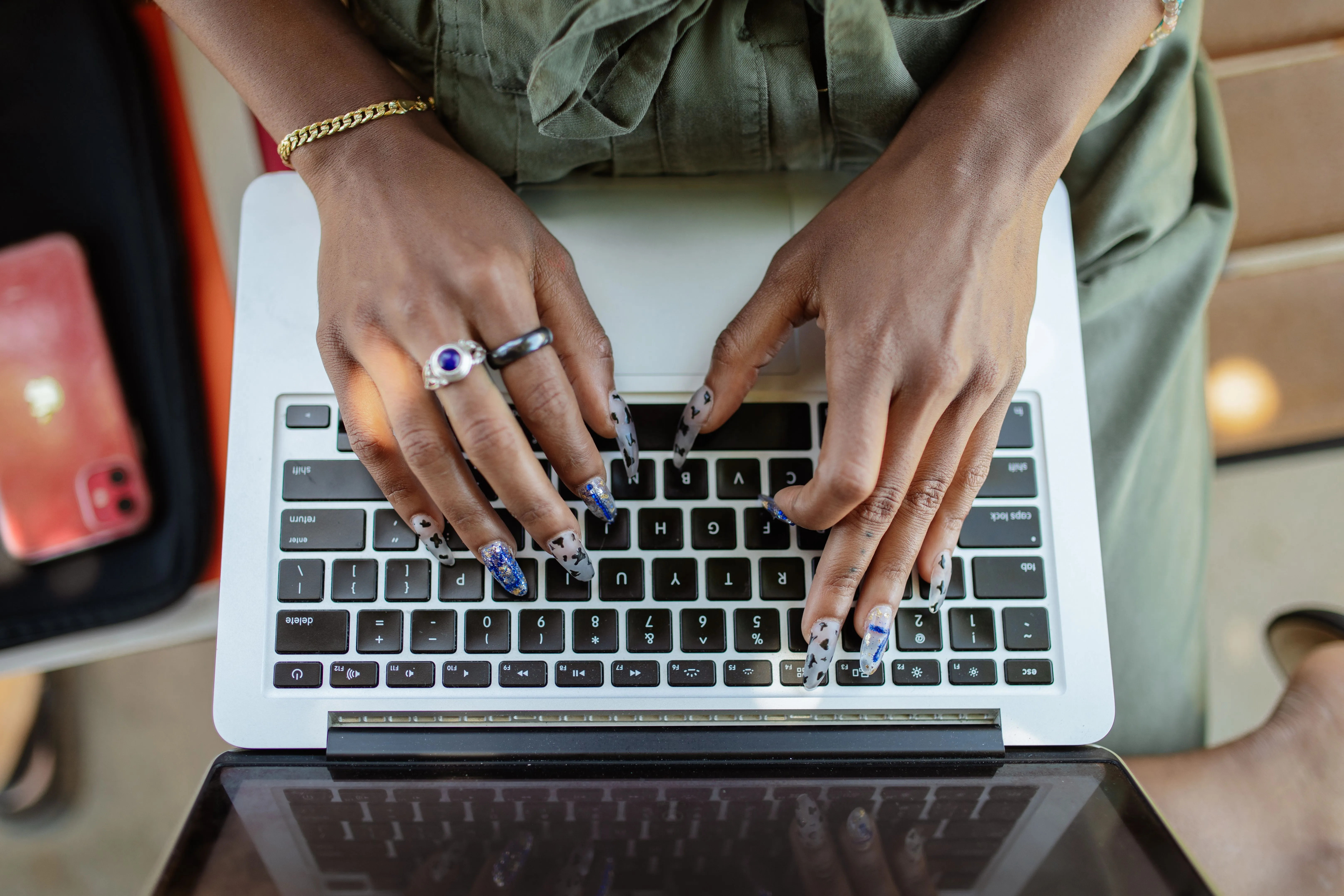 Hands with silver rings typing on a laptop keyboard, seen from above