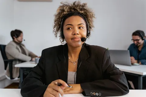 A frontline worker in a headset at her desk, with two colleagues working behind her