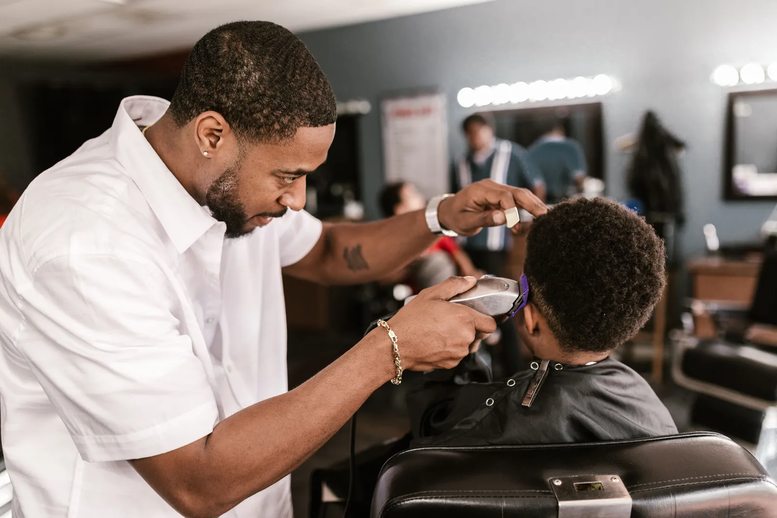 A barber at work on a child’s haircut in a busy neighbourhood shop