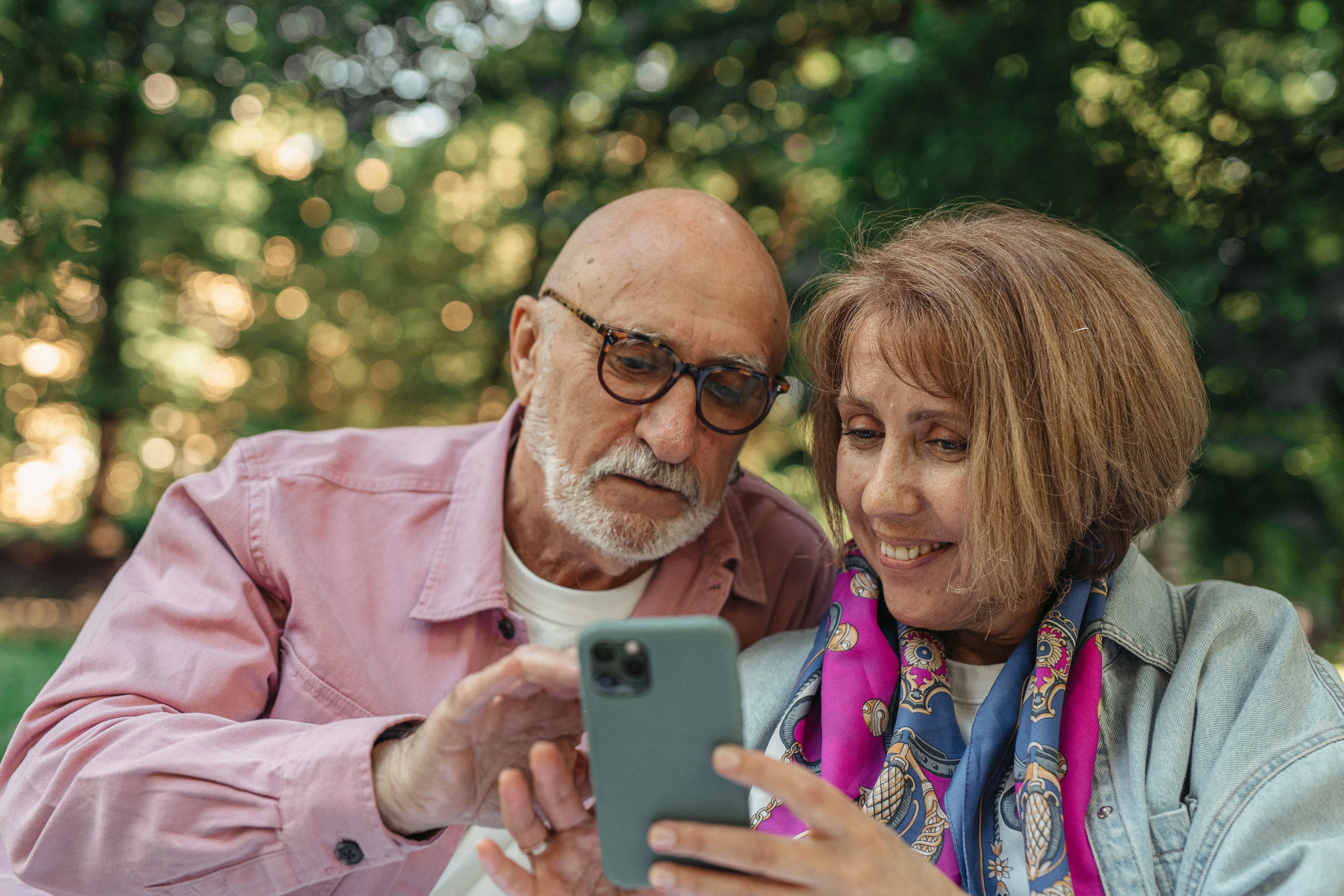 A senior couple outdoors smiling at a smartphone together